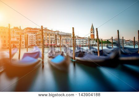Venice cityscape view on Grand canal with colorful buildings, gondolas and San Marco campanille at the sunset. Long exposure image technic with motion blurred boats and glossy water