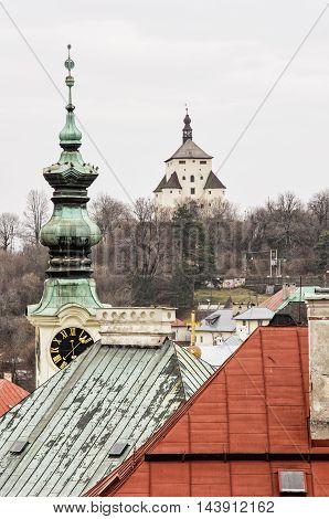 New castle and church tower with clock in Banska Stiavnica Slovak republic. Architectural theme. Old buildings. Travel destination. Cultural heritage. Vertical composition.