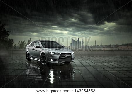 Moscow, Russia - June 18, 2016: Gray car Mitsubishi Lancer stay and reflect in wet road in heavy rain at daytime on Moscow city