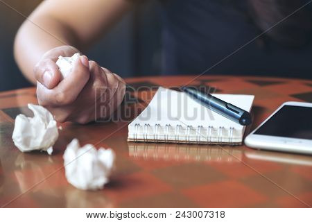 Closeup Image Of A Businesswoman Screwed Up Papers On Table With Notebook And Mobile Phone