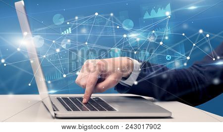 Businessman typing on laptop with linked reports charts grapghs around