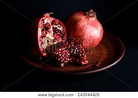 Ripe And Tasty Pomegranate In A Plate On A Black Table