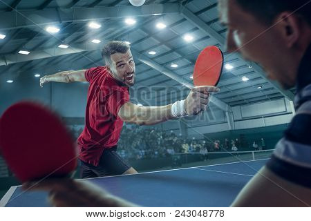 The Table Tennis Player In Motion. Fit Young Sports Man Tennis-player In Play On Sport Arena Backgro