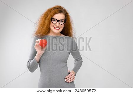 Charming Young Girl With Red Hair. A Young Girl In A Gray Sweater. Young Girl On A Gray Background.
