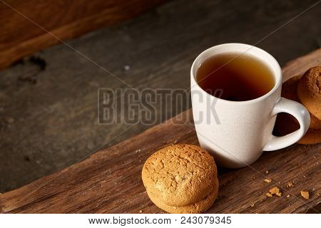 White Porcelain Mug Of Black Tea Or Earl Grey And Pile Of Sweet Cookies On Flat Piece Of Wood Over R
