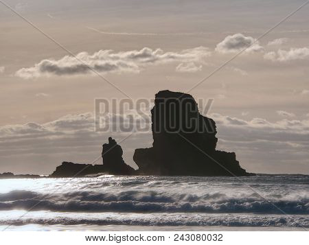 Sharp Silhouette Of A Cliff Against The Background Of Sunset. Sea Waves Break On The Rocks. Talisker