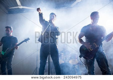Lead Singer And Guitarists Playing Hard Rock Music On Stage At Music Festival