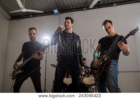 Lead Singer With Guitarists Performing Rock And Roll Music On Stage At Music Festival