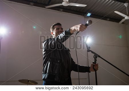 Rock Band Lead Singer Pointing Mic Towards Audience During Live Concert