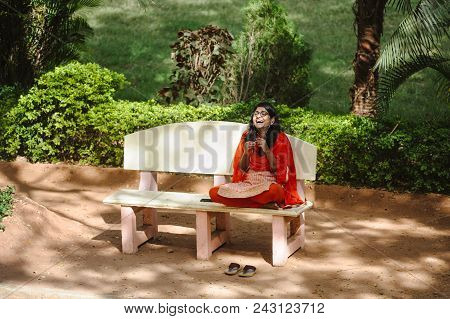 Indian Woman In Sari Sits In Outdoor And Laughing While Speaks Cellphone. 8 February 2018 Sai Baba A