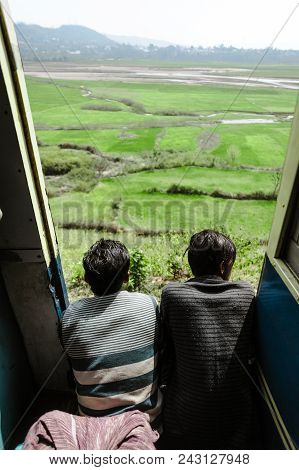 Two Indian Boys In Train Doors And Lookint Ant Beautiful Green Landscape. 27 February 2018 Amritsar,