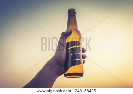 Human Hand Holding Yellow Empty  Beer Bottle