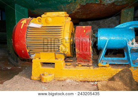 Old Yellow Electric Motor Connected With A Pump Blue.