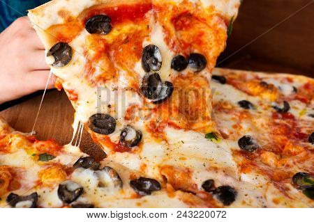 A Child Picking Up A Slice Of Large Margherita Pizza With Black Olives. Melted Cheese.