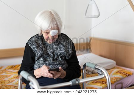 Lonley Elderly 95 Years Old Woman Sitting At The Bad Using Modern Mobile Phone Application To Monito