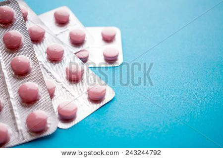 Close Up Pink Tablets In Silver  Blister Pack On Blue Background. Unused Or Expired Prescription Dru