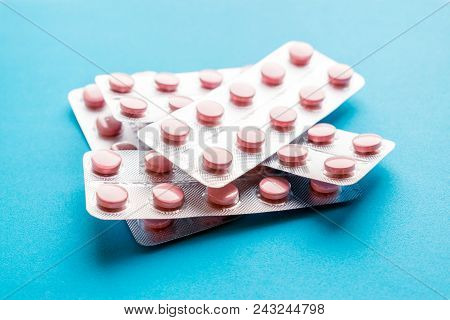 Close Up Pink Tablets In Silver  Blister Pack On Blue Background. Unused Or Expired Prescription Dru