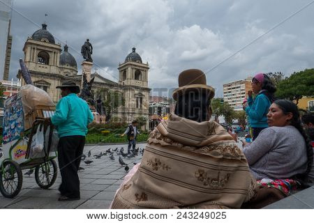 LA PAZ, BOLIVIA - 24 MARCH, 2018: Two indigenous bolivian women sit on the stairs at Plaza Murillo