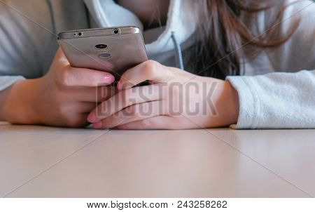 Young Seriously Woman Reading Something On Her Mobile Phone Sitting In Cafe. Closeup Hands