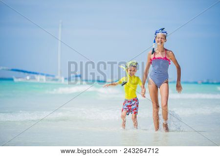 Brother And Sister Playing And Having Fun On The Beach During The Hot Summer Vacation Day.