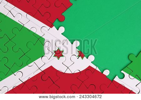 Burundi Flag  Is Depicted On A Completed Jigsaw Puzzle With Free Green Copy Space On The Right Side.