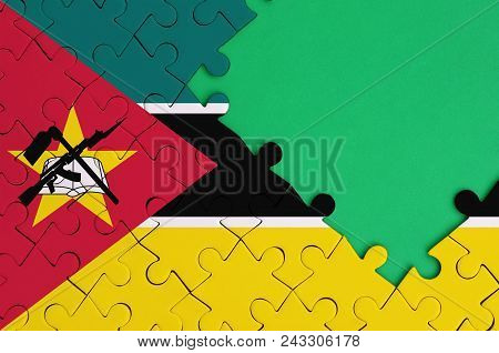 Mozambique Flag  Is Depicted On A Completed Jigsaw Puzzle With Free Green Copy Space On The Right Si