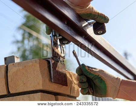 The Worker Installs Rollers On The Sliding Gate .