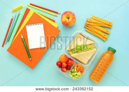 School Supplies And Lunch Box With Sandwiches, Pieces Of Cucumbers And Carrots, Apricot, Cherries, A