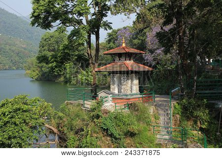 Green Shore Of Lake Fewa, Pokhara. Small Hindu Temple And Flowering Trees.