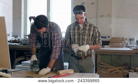 Two Carpenters Working With Wooden Planck And Electric Planer In