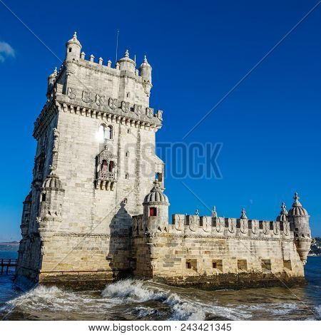 Bottom View Of Lisbon Torre De Belem With Blue Sky And Breaking Waves