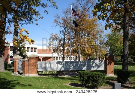 Defiance College Sign And Flag Pole With The United States Of America Flag Surrounded By Fall Foliag