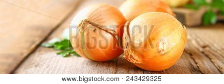 Yellow Onion With Parsley On A Wooden Table
