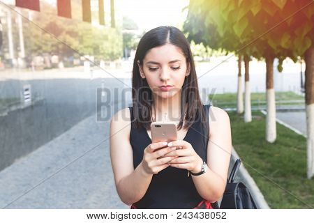 Happy Girl Texting On A Smart Phone Leaned On Marble Wall In City