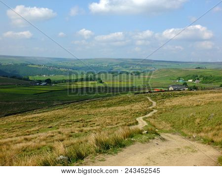 A Long Winding Footpath Running Downhill In Stoodley Moor In Yorkshire With Fields And Farms In The 