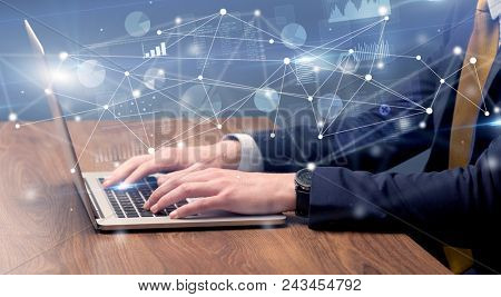 Businessman typing on laptop with linked reports charts grapghs around