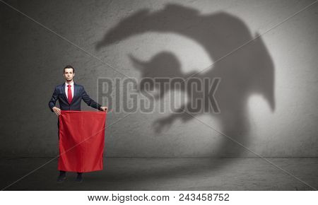Businessman standing with red cloth in his hand and imp shadow on the background