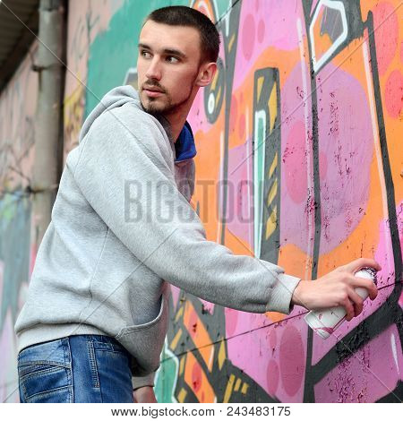 A Young Graffiti Artist Looks Around While Drawing. Vandal Tries To Be Undetected While Drawing The 