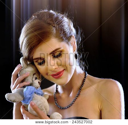 Woman in love. Beautiful girl with gift from boyfriend after first date. Children toy teddy bear as symbol childhood and romantic relationship on black background. First weeks of pregnancy.
