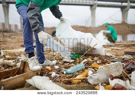 Worker of nature protection company taking plastic bottle from littered ground
