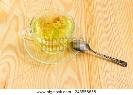 Linden Flower Tea In The Transparent Glass Cup On Saucer With Tea Spoon On A Light Colored Wooden Su