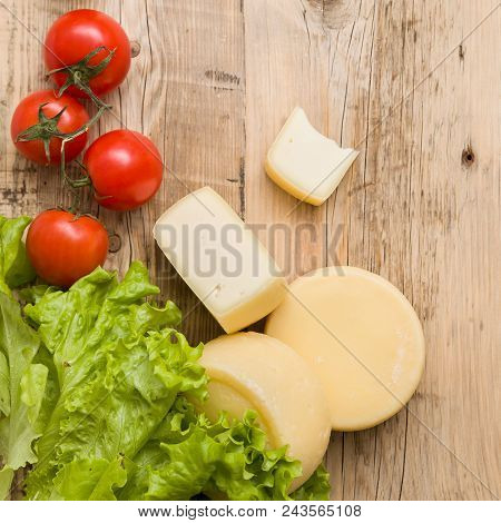 Above View On Fresh Heads Of Homemade Cheese, Organic Tomatoes And Salad Leaves On Wooden Table Back