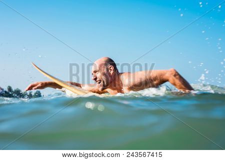 A senior man on a surfboard