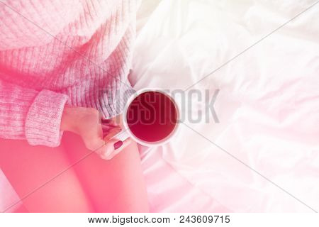 Girl In Bed Wearing Wool Sweater Holding Cup Of Coffee