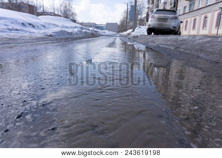 The Stream Flows On The Road Through Puddles At A Pedestrian Crossing. It's Spring.