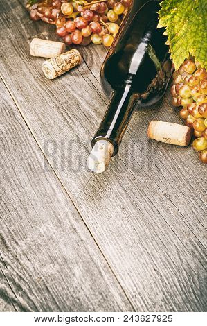 Pouring White Wine Into The Glass Against Wooden Background