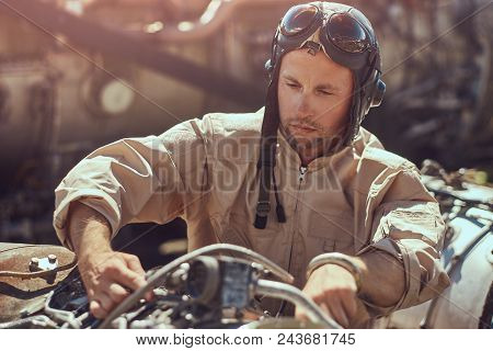 Portrait Of A Pilot-mechanic In Uniform And Flying Helmet, Repairing The Dismantled Airplane Turbine