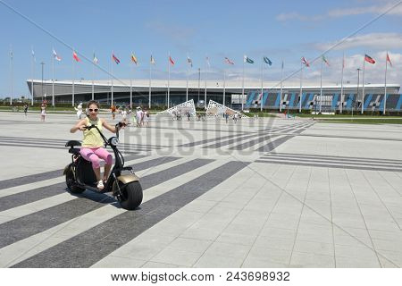 SOCHI, RUSSIA - JUL 09, 2017: girl on electric scooter on background of sports stadium