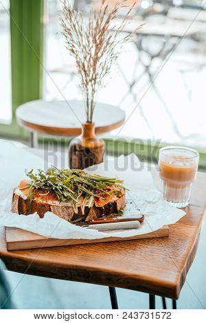 Cup Of Beautiful Cold Ice Latte And Toast With Prosciutto And Ruccola With Wooden Vase Distichlis Sp