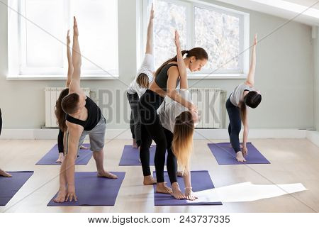 Young Female Yoga Instructor Teaching Utthita Trikonasana Pose, Extended Triangle Exercise For A Gro